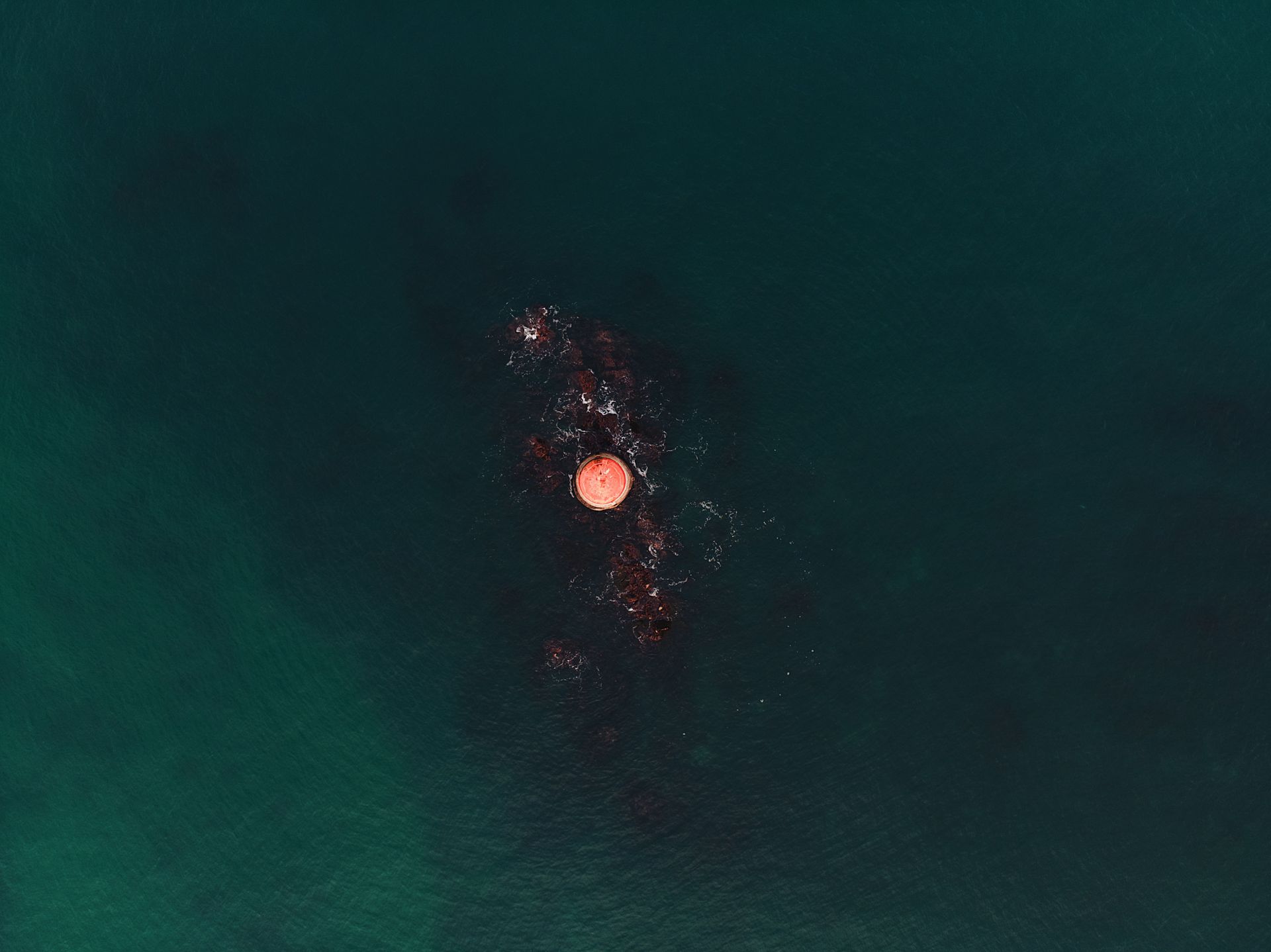 An unmanned aerial vehicle flying low over the ocean surface to relay data from below